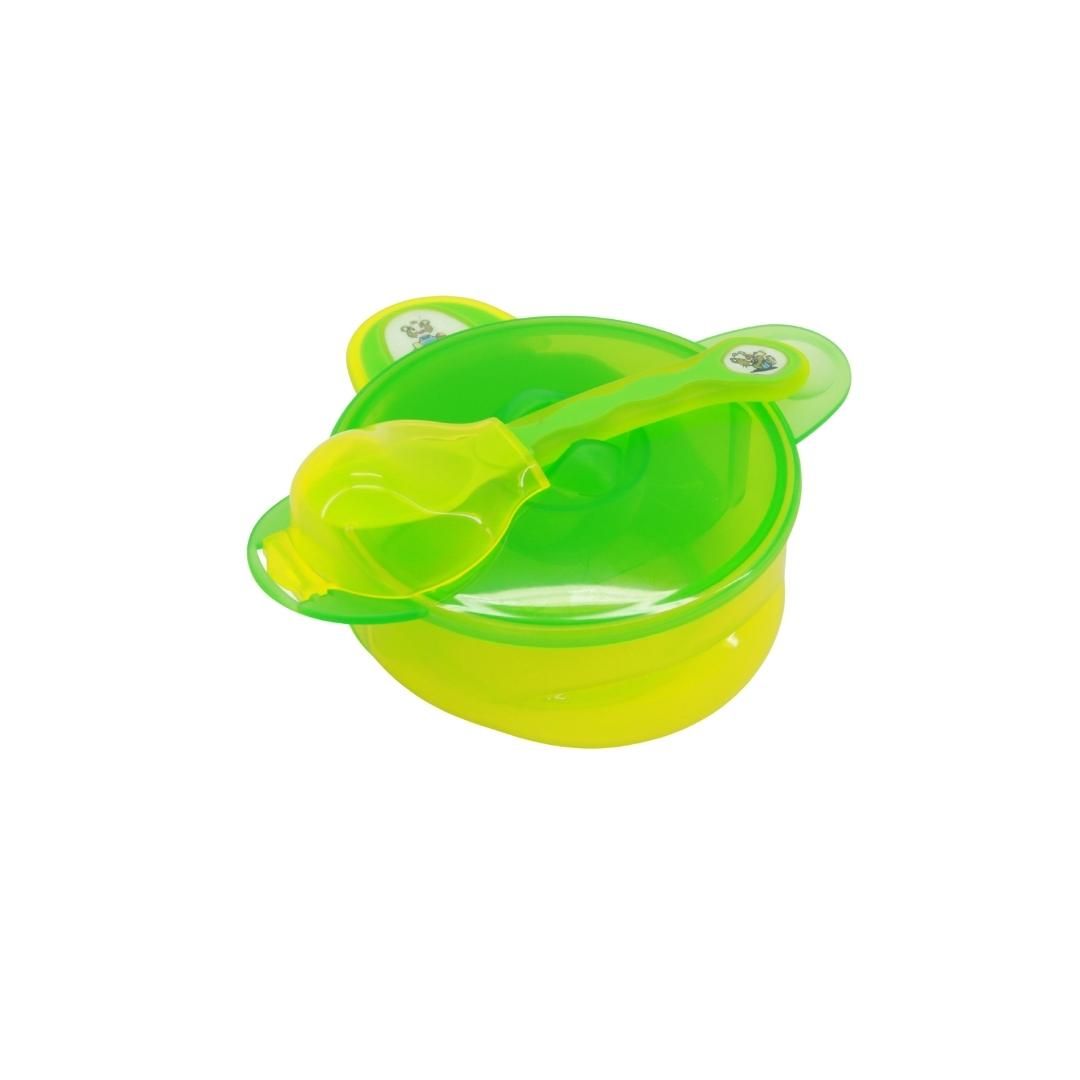 Grünes und gelbes Baby-Set mit Schüssel, Deckel und Löffel. Der Löffel liegt in der Schüssel. Der Deckel ist teilweise geöffnet.