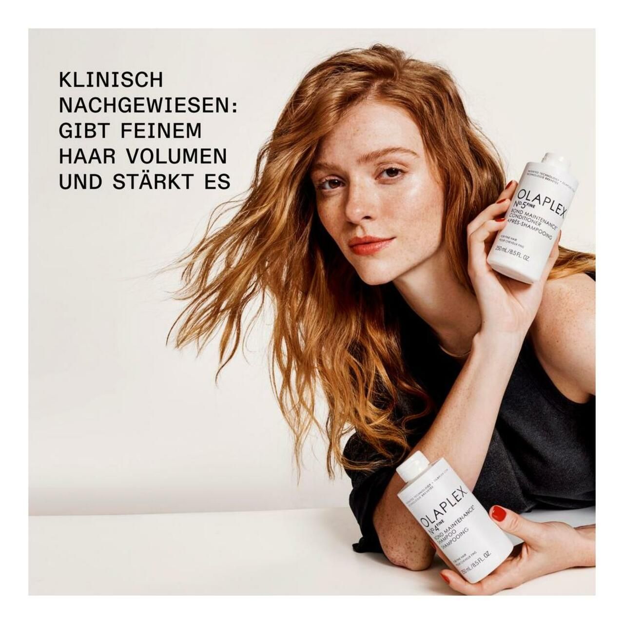 Frau mit langen, welligen, roten Haaren hält zwei Flaschen Olaplex No.4 Fine Bond Maintenance Shampoo. Text: Gibt feinem Haar Volumen und stärkt es.