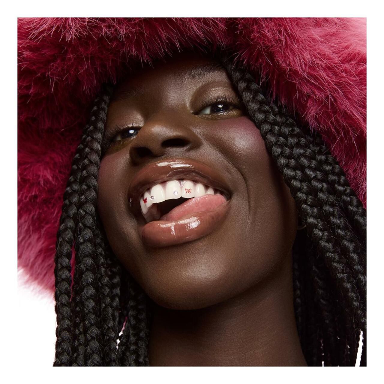 Frau mit Lancôme Juicy Tubes Lipgloss. Glänzende Lippen. Roter Hut. Dunkle Haut.