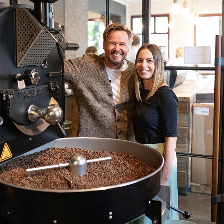 Ein Mann und eine Frau stehen neben einer Kaffeeröstmaschine.