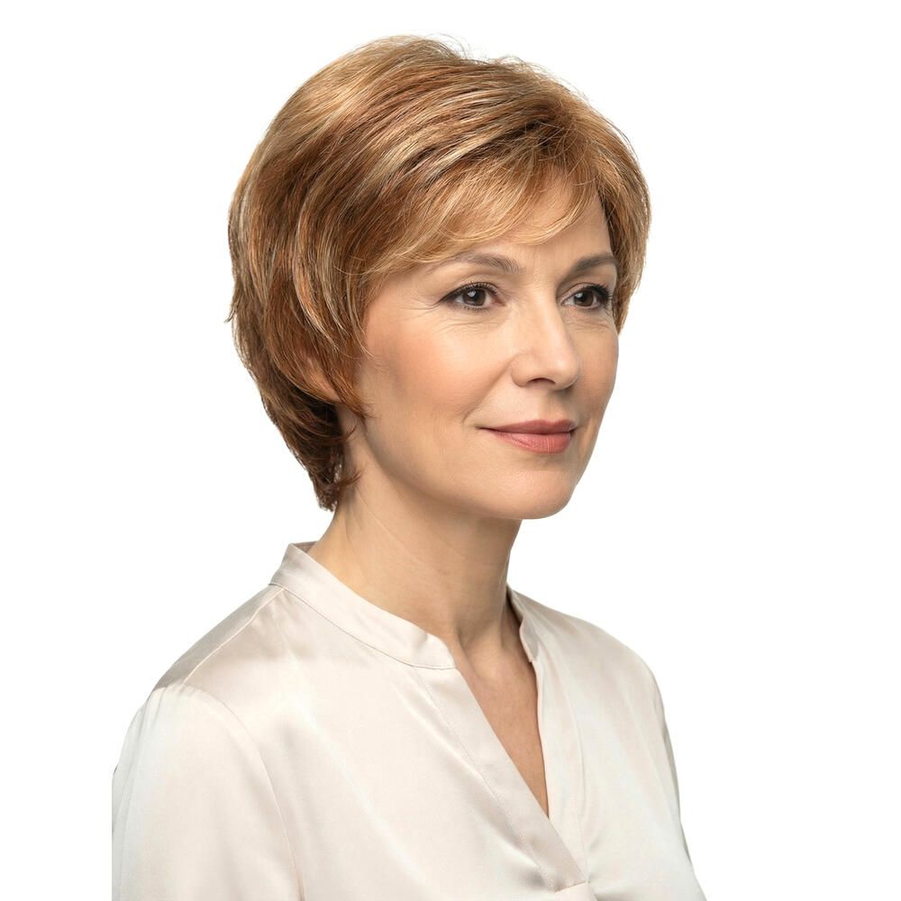 Frau mit Perücke, blond-braune Haare, Dreiviertelansicht. Hellbraune Strähnen, schulterlange Frisur. Trägt eine helle Bluse.