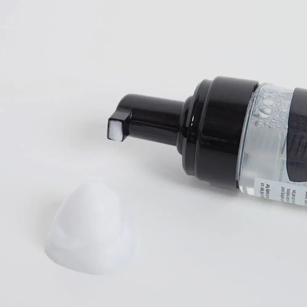 Schaum aus einer Flasche. Schwarzer Pumpkopf, weißer Schaum. Aufschrift nicht lesbar.