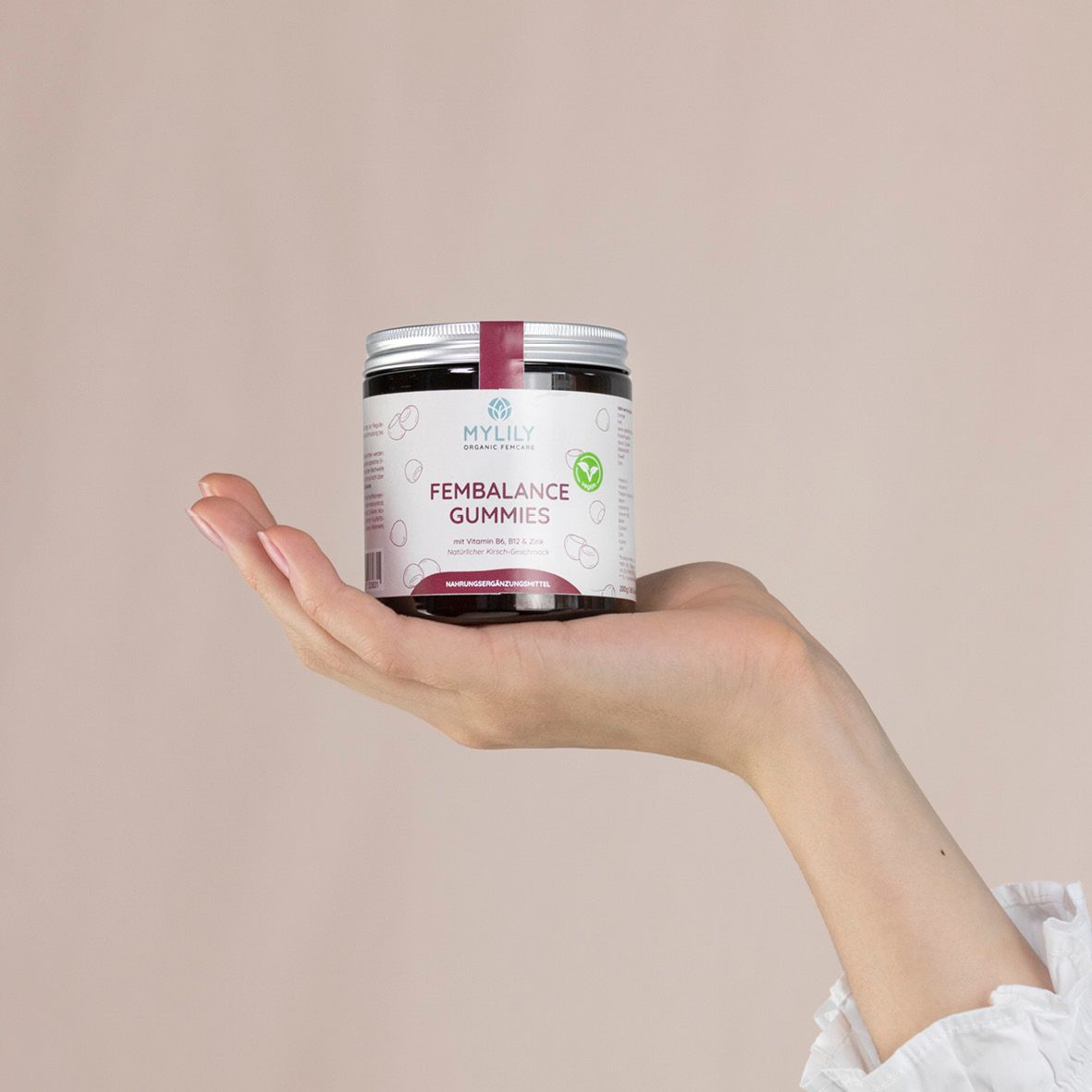 Hand hält eine Dose MYLILY Fembalance Gummies. Aufschrift: Fembalance Gummies. Dose mit rotem Deckel und weißem Etikett.