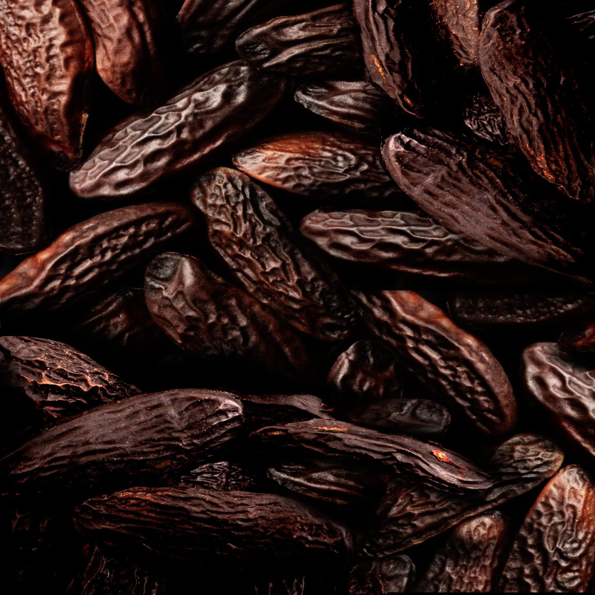 Nahaufnahme von braunen, länglichen Bohnen. Dunkler Hintergrund.