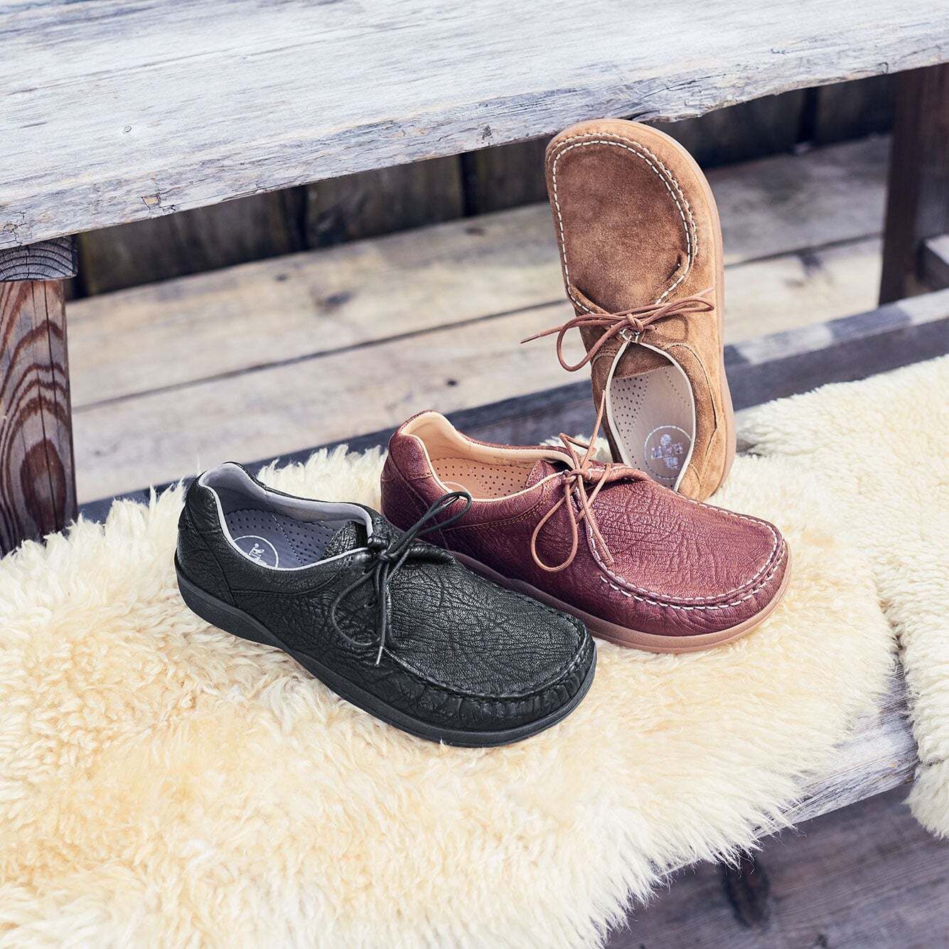 Drei Lederschnürschuhe. Schwarz, Braun und Beige. Breite Passform. Auf Holz und Fell. Schnürsenkel.