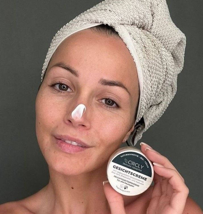 Frau mit Handtuch auf dem Kopf. Creme auf der Nase. Hält einen Tiegel mit Aufschrift CIRCLY Gesichtscreme.