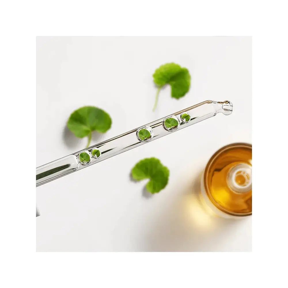 Pipette mit goldenem Serum und grünen Blättern.