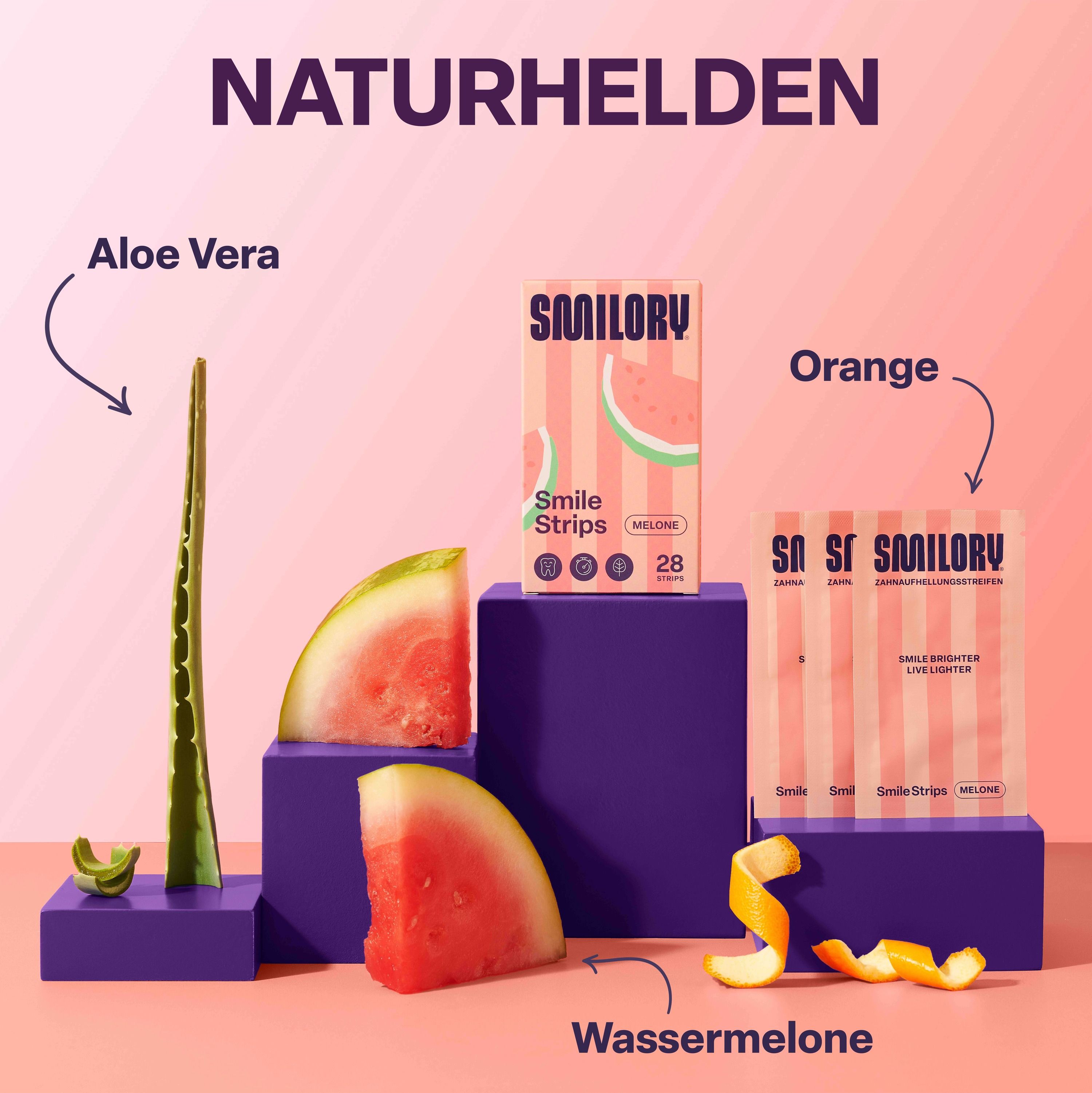 Produkt-Arrangement mit Smilory® Smile Strips. Wassermelone, Aloe Vera und Orange neben Produktverpackungen. Text: Naturhelden, Smilory®.
