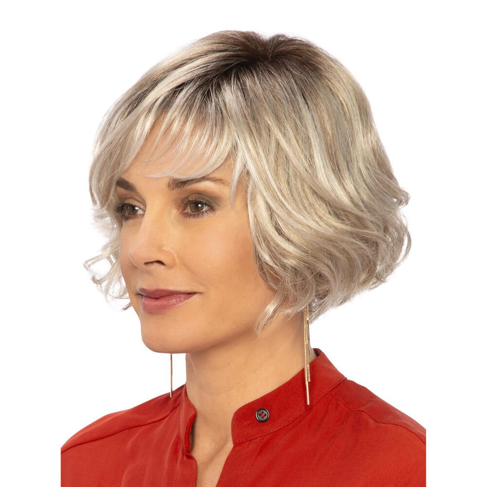 Perücke Biarritz von DELUXE. Blond gewellt, mit Pony. Frau mit roter Bluse. Seitenansicht.