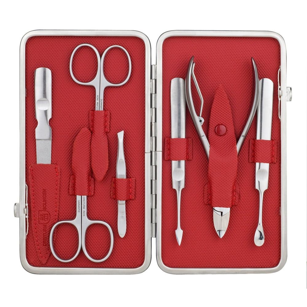 Maniküre-Etui, rot ausgekleidet, mit sieben silberfarbenen Werkzeugen. Enthalten sind Schere, Pinzette, Nagelhautschieber und -schneider.