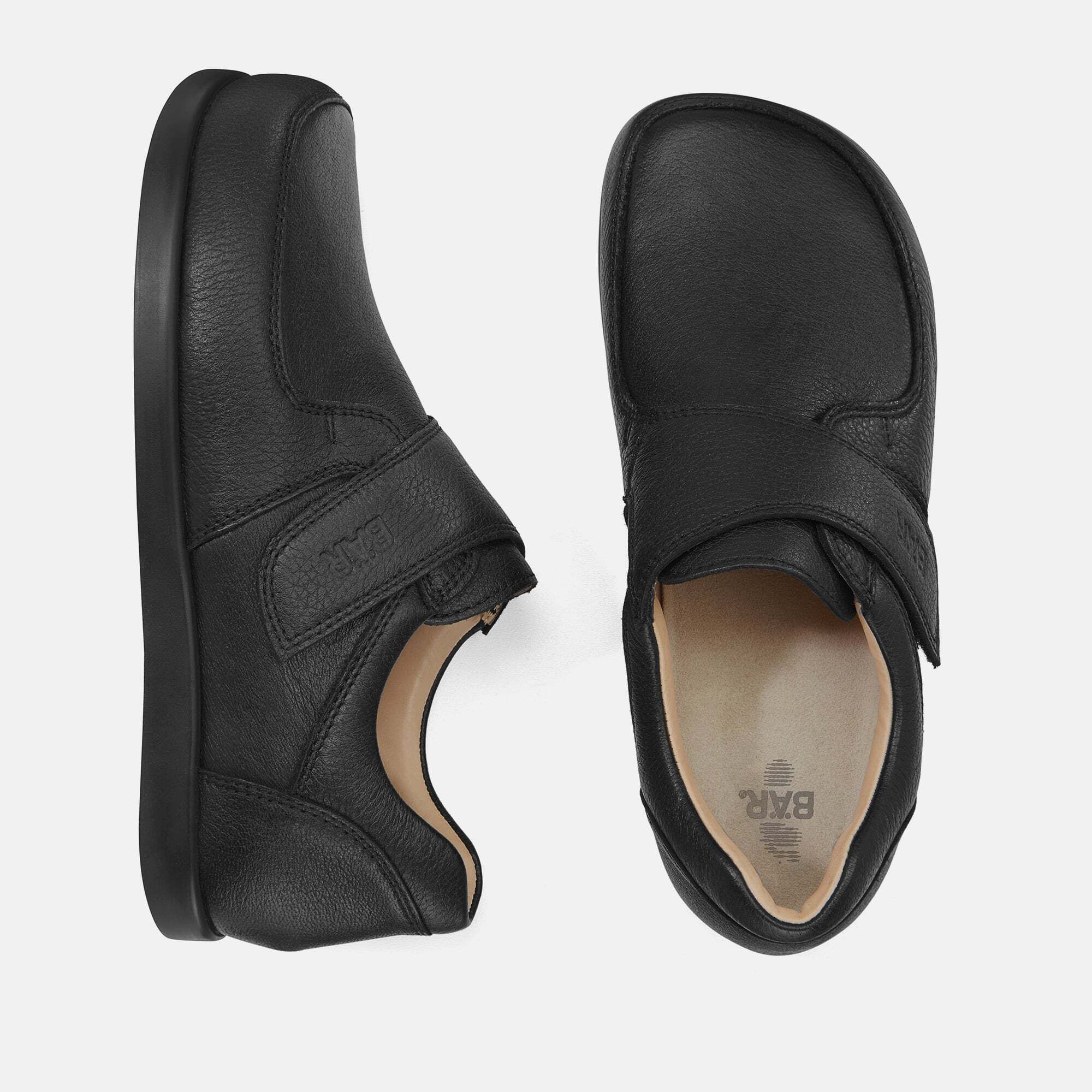 Schwarze Herren-Slipper, Draufsicht. Klettverschluss. BÄR-Logo. Breiter Schnitt. Leder. Hellbraunes Innenfutter. Rechteckige Schuhspitze.