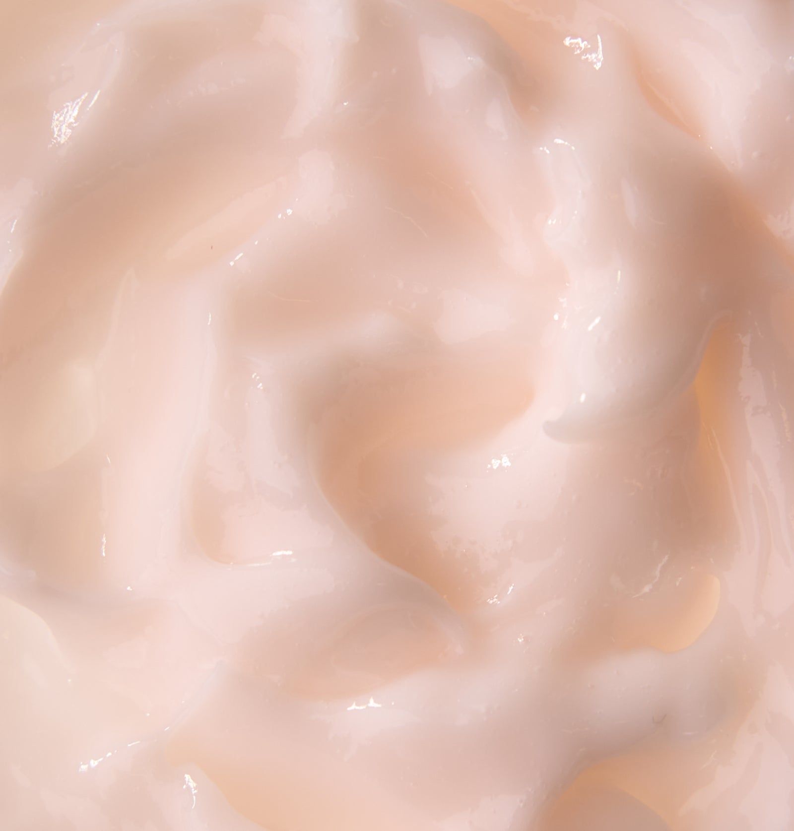 Nahaufnahme einer cremigen, hellrosa Haarmaske. Die Textur ist glatt und cremig.