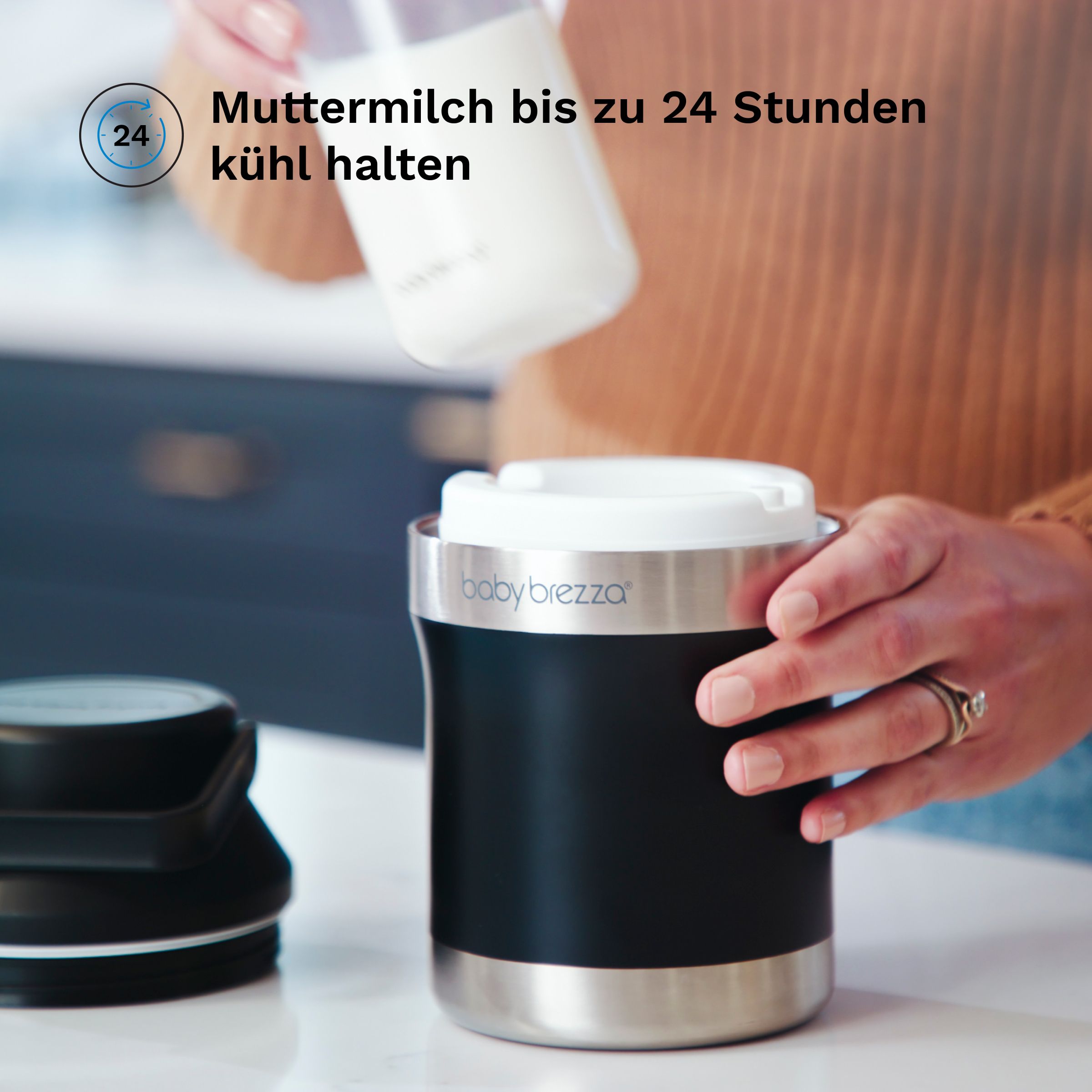 Person setzt eine Milchflasche in einen schwarzen Behälter ein. Baby Brezza Logo.