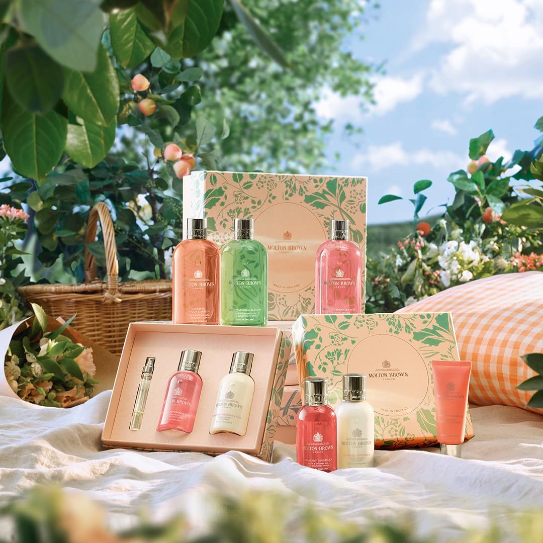 Molton Brown Produkte auf Picknickdecke. Verschiedene Flaschen und Geschenkboxen. Grün, rosa und weiß. Text.