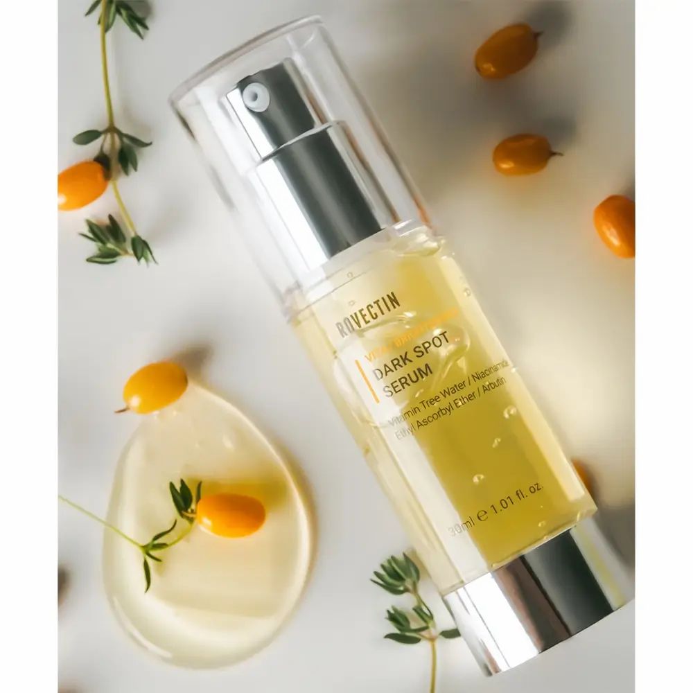 Serumflasche mit Pumpe, umgeben von Früchten und Blättern. Aufschrift: ROVECTIN Dark Spot Serum.