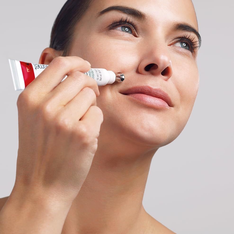 Frau hält Cellfiller-XT. Tube mit Applikator wird auf die Haut aufgetragen. Grauer Hintergrund.