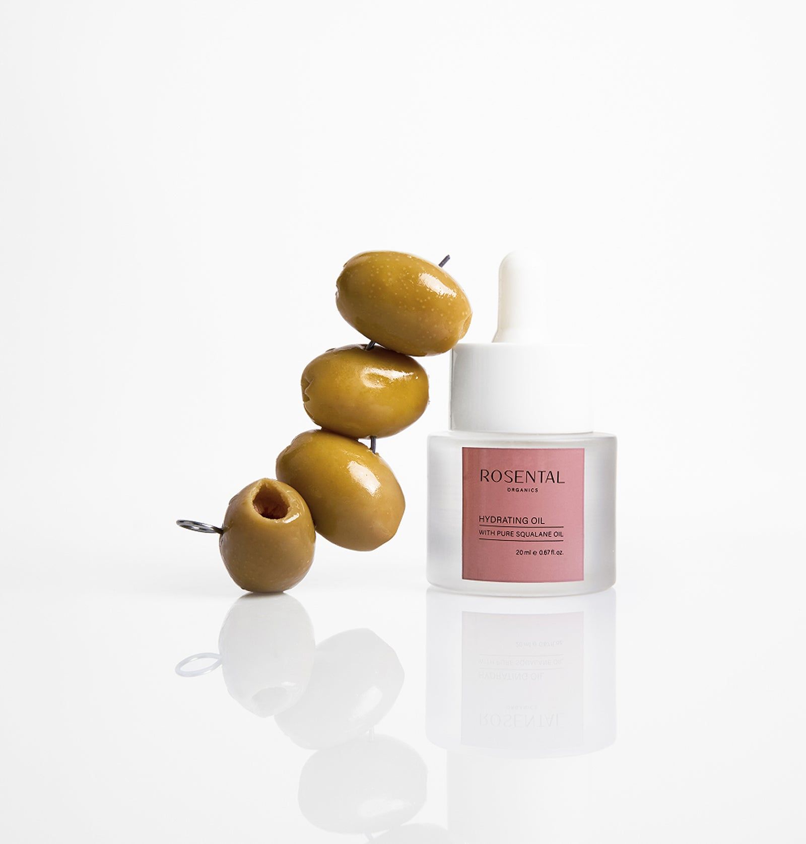 Glasflasche mit Oliven und Spieß. Rosa Etikett mit Text. Weißer Hintergrund.