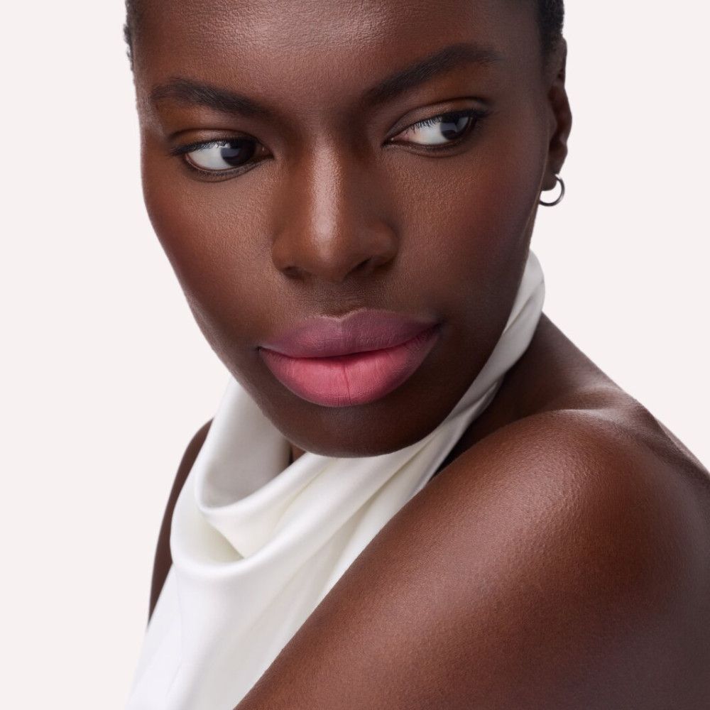 Porträt einer Frau mit Catrice Blur-Real Matt Lippenstift. Rosa Lippen, Blick zur Seite, weißes Oberteil.