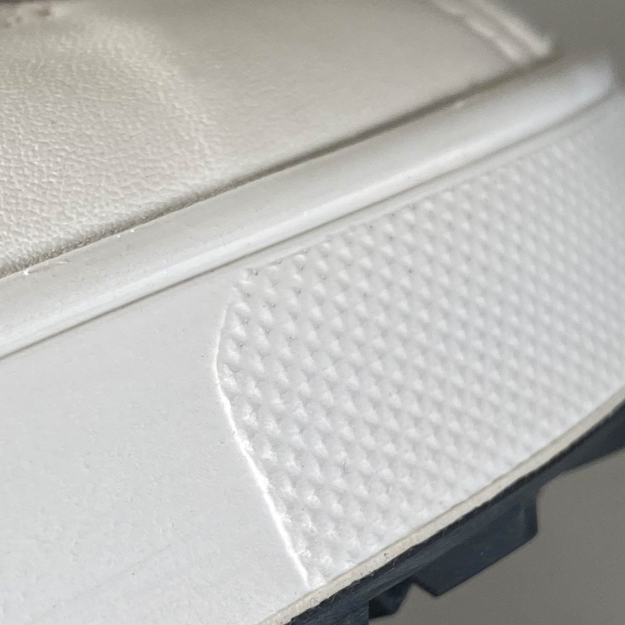 Nahaufnahme der Sohle eines weißen Schuhs. Weiße Sohle mit geprägtem Muster und schwarzem Gummi.