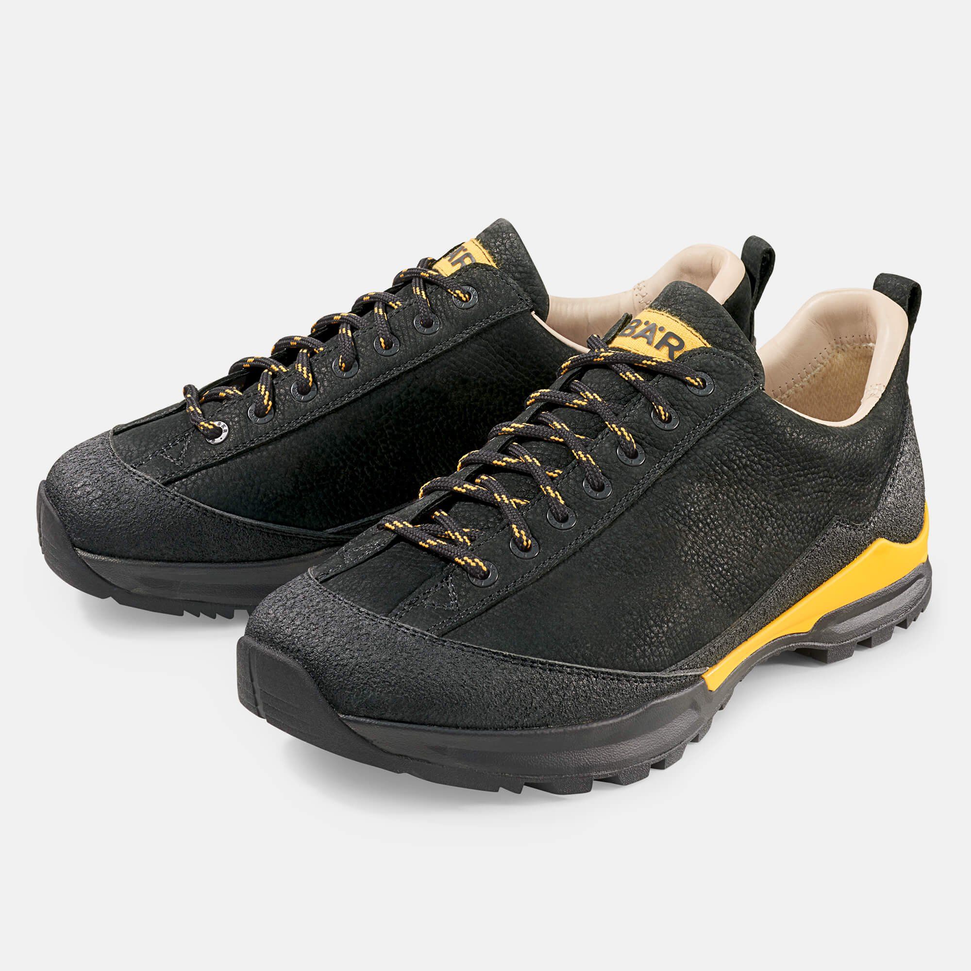 Paar schwarze Wanderschuhe mit gelben Akzenten. Gelb-schwarze Schnürsenkel. BÄR-Logo auf der Zunge.
