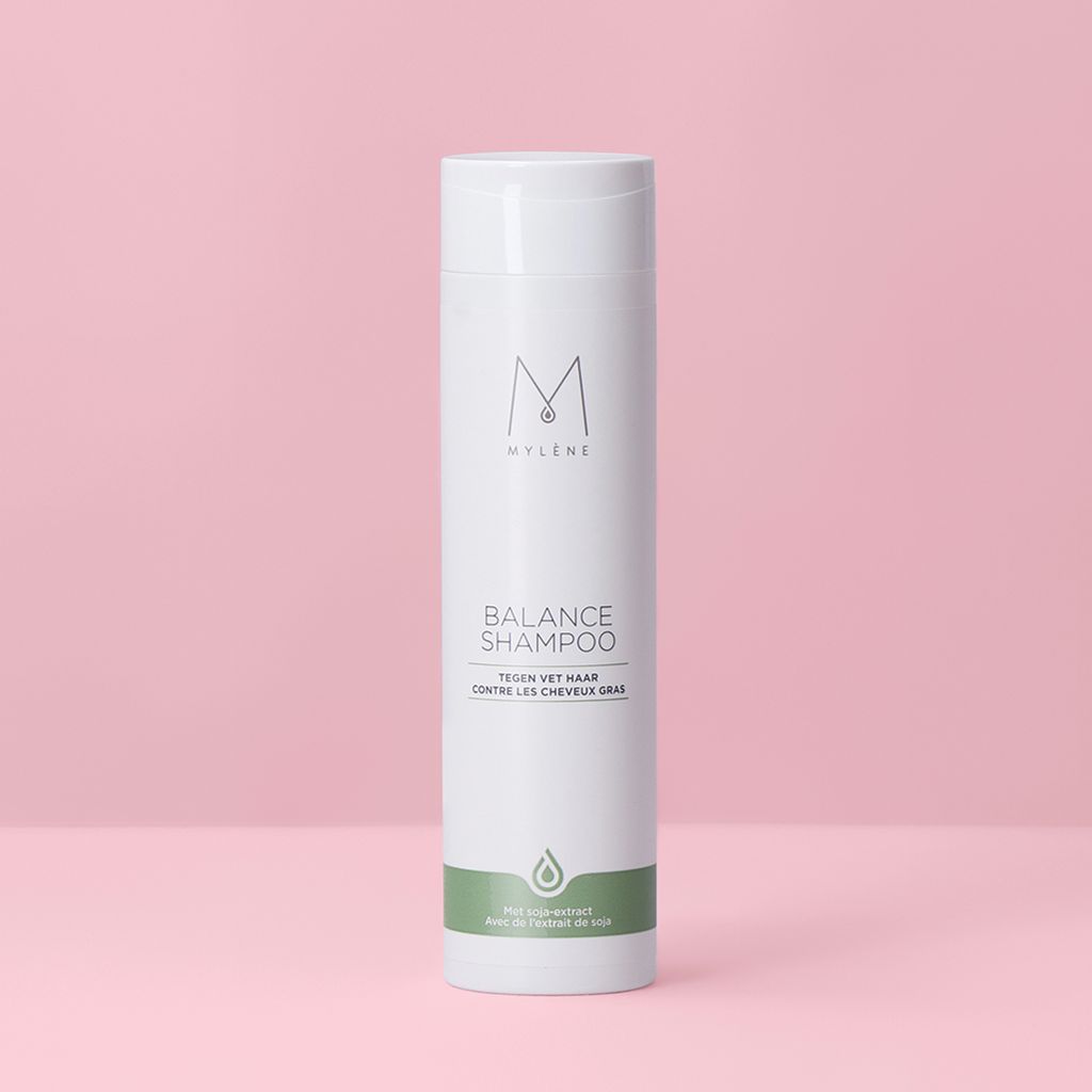 Weißes Shampoo mit grünem Streifen. Text: Balance Shampoo, gegen fettiges Haar. Logo: M. Flasche steht vor rosa Hintergrund.