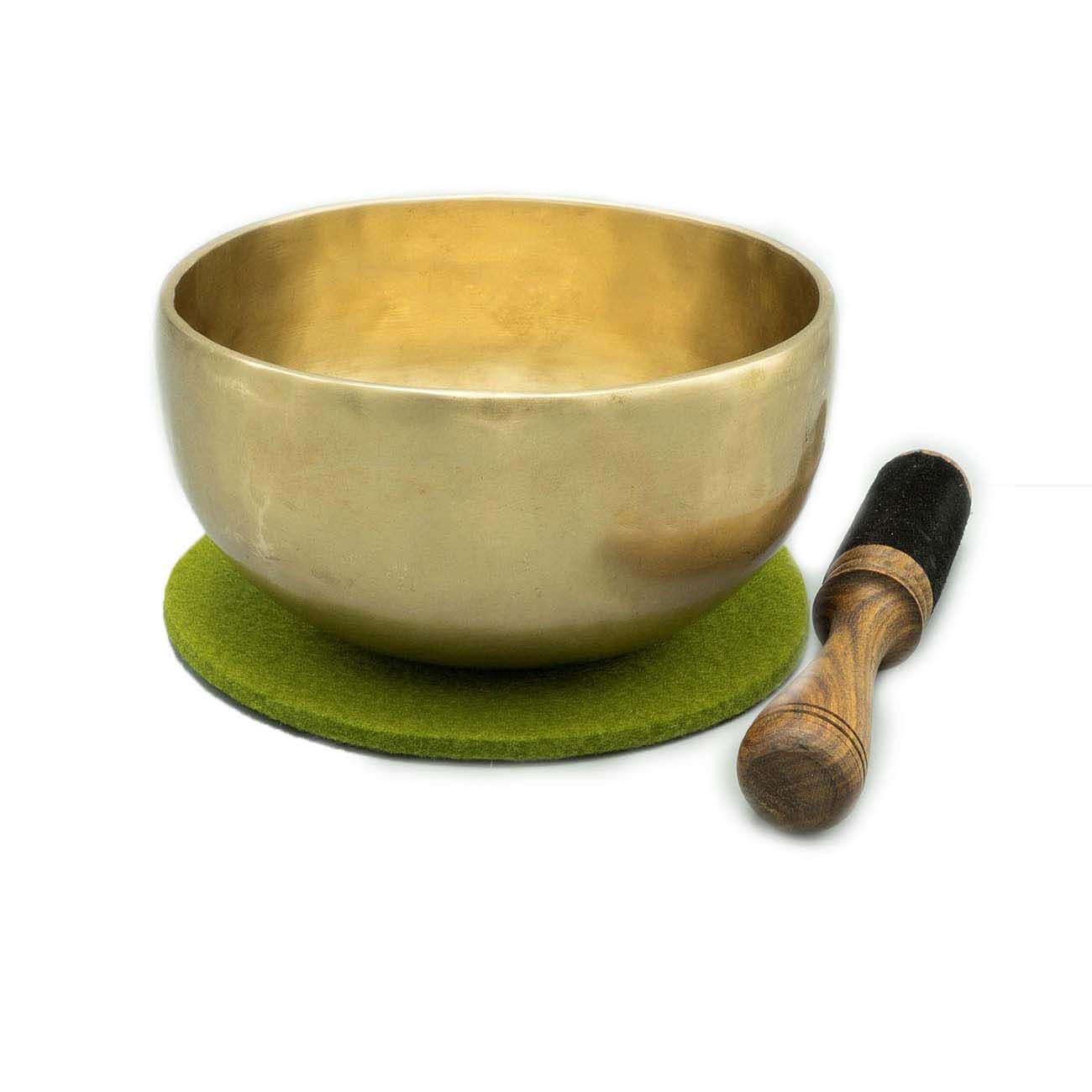 Goldfarbene Klangschale mit grünem Filzuntersetzer und Holzschlägel mit schwarzem Kopf. Auf weißem Hintergrund.