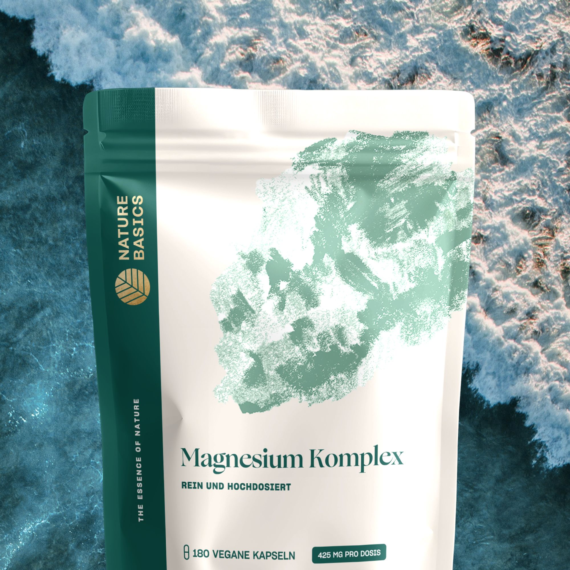 Standbodenbeutel mit Magnesium Komplex vor dem Hintergrund einer Meeresbrandung. Der Beutel hat eine dunkelgrüne und weiße Farbgebung.