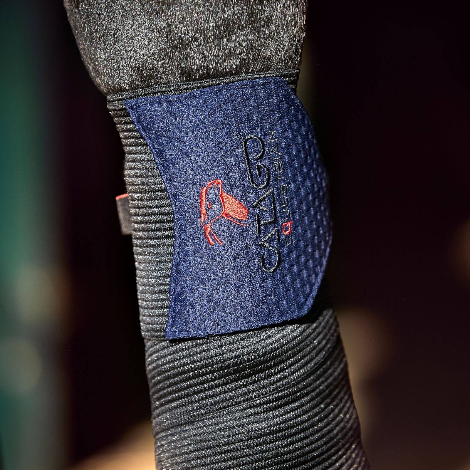 Bandage am Bein. Schwarzes Material mit blauem Patch. Rotes Logo: CATAGO FIR-Tech Healing.