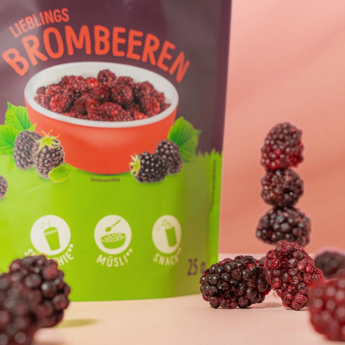 Nahaufnahme von gefriergetrockneten Brombeeren und einer Packung NutriPur Frucht Snacks. Brombeeren in einer Schale und gestapelt.