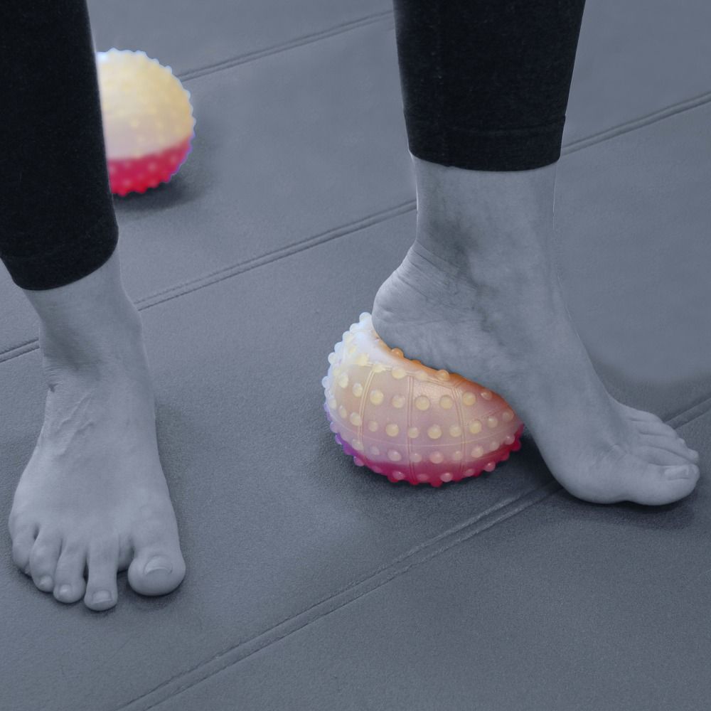 Ein Fuß auf einem Gewichtsball Fluisense. Gelb-rosa, mit Noppen. Zweiter Ball im Hintergrund.