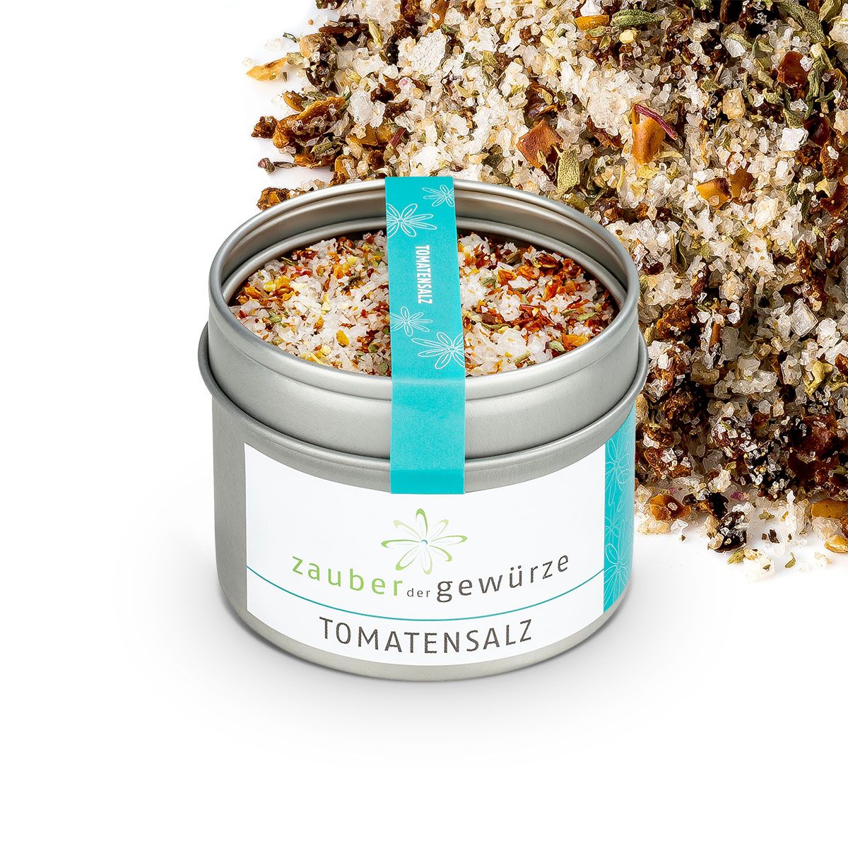 Geöffnete Dose Tomatensalz. Türkisfarbenes Etikett mit Produktname und Logo. Salz und Gewürze liegen neben der Dose.