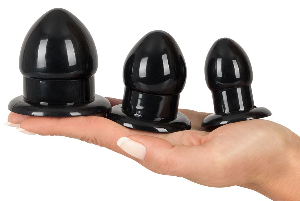 Drei schwarze Anal-Plugs in verschiedenen Größen, gehalten in einer Hand.