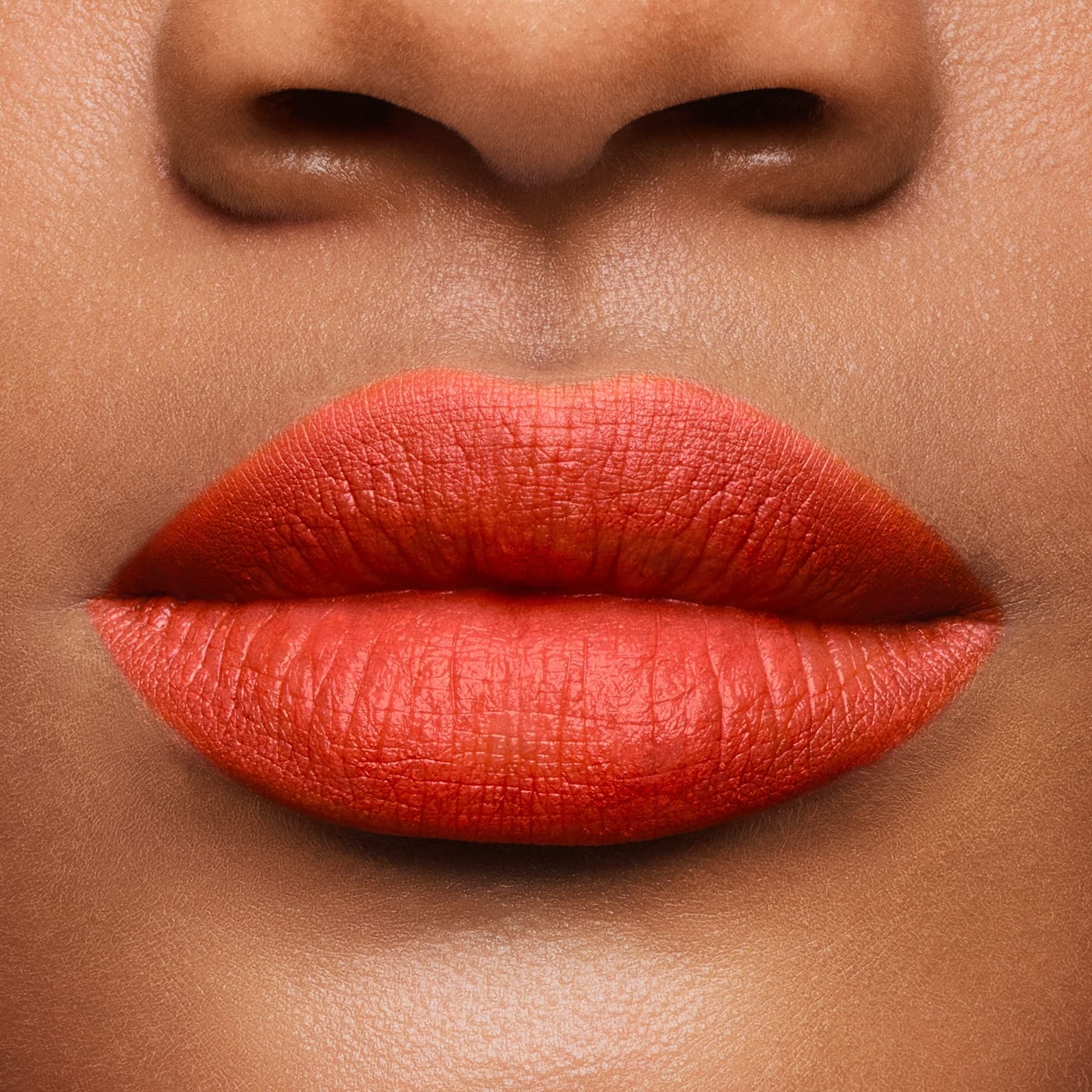 Nahaufnahme von Lippen, die mit orangefarbenem Lippenstift bedeckt sind. Hautton.
