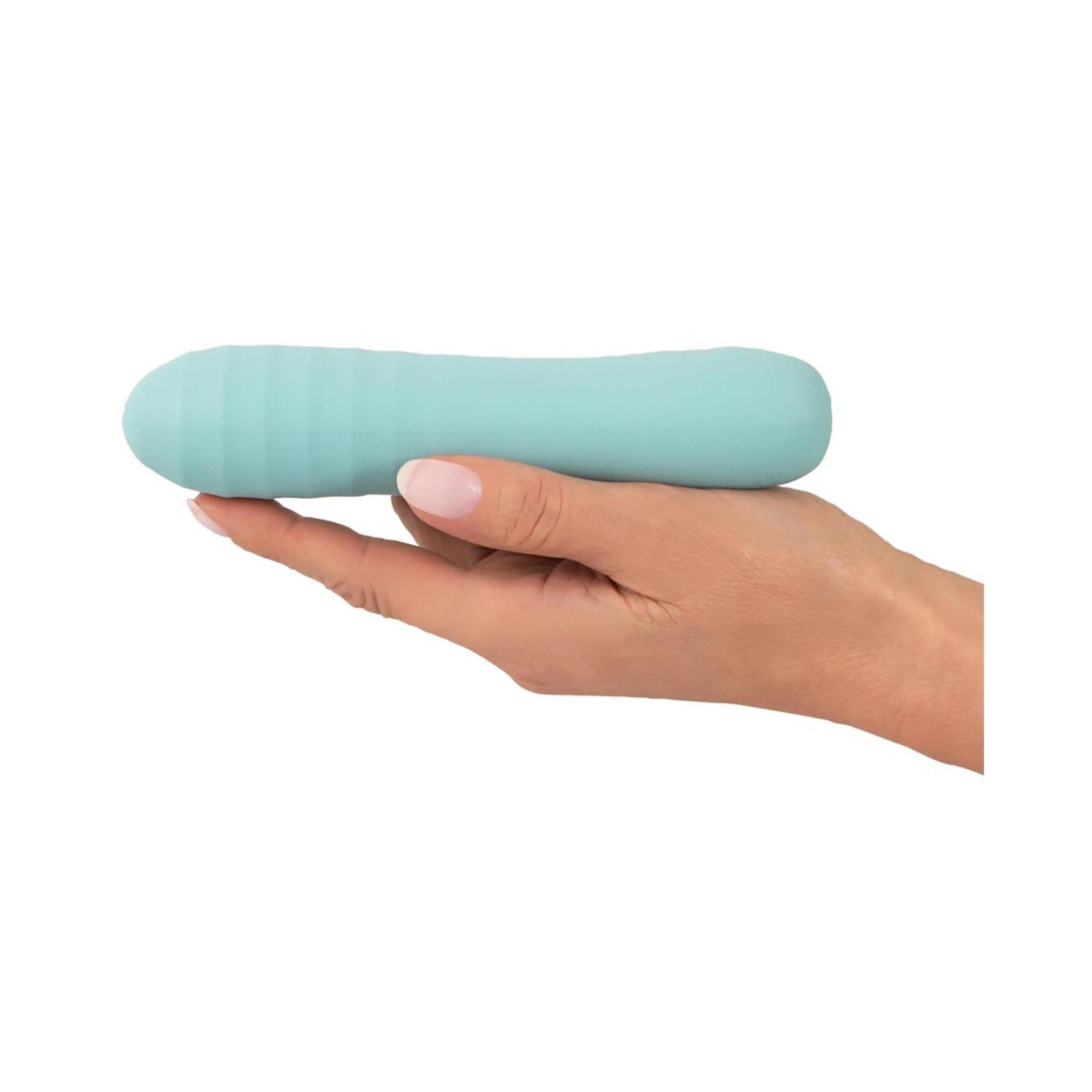 Türkisfarbener Vibrator in einer Hand gehalten. Geriffelte Spitze, glatter Schaft.