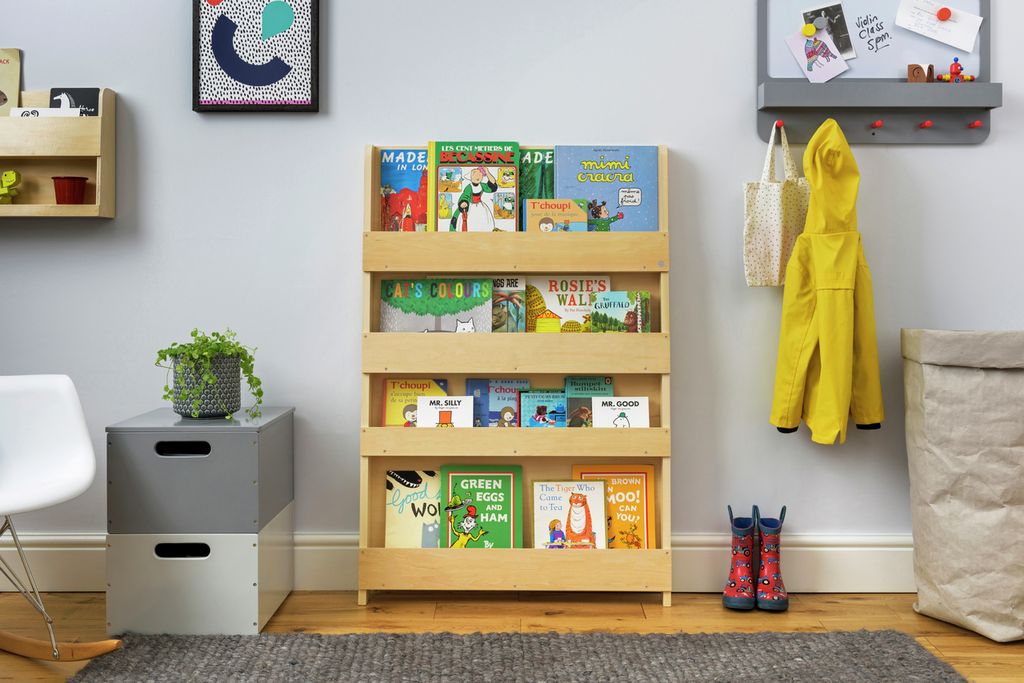 Bücherregal aus Holz in einem Kinderzimmer. Bücherregal mit Büchern, neben einem Stuhl, Spielzeug und Kleidung.