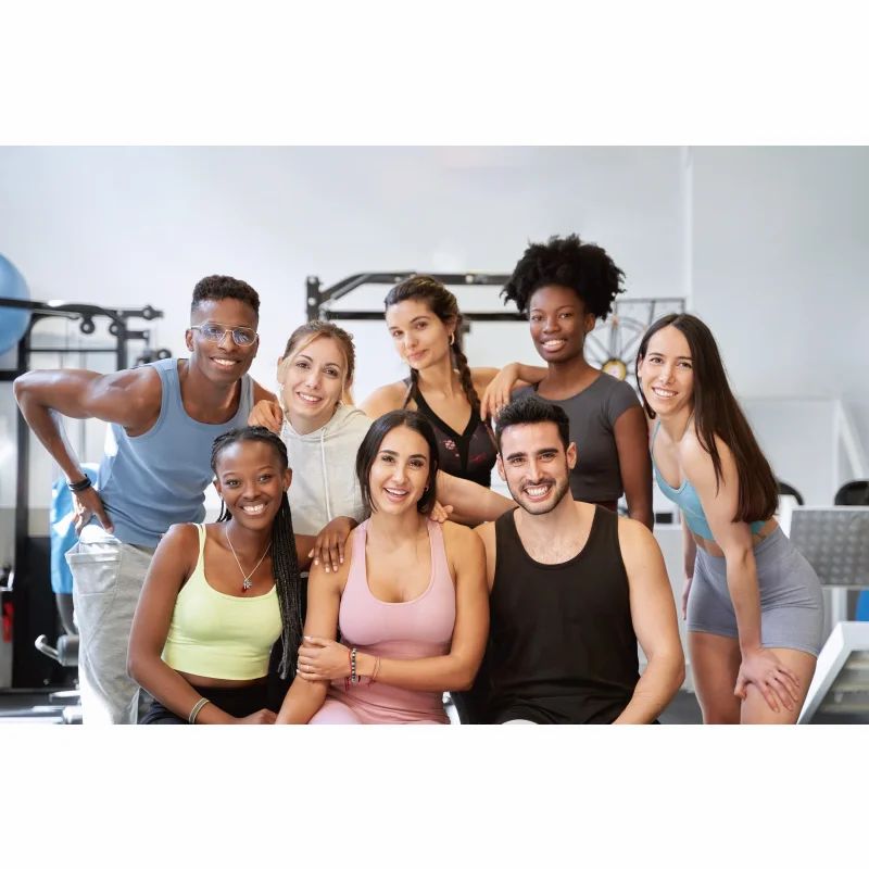 Gruppe von Menschen in Sportkleidung, lächelnd in einem Fitnessstudio. Fitness-Kontext.