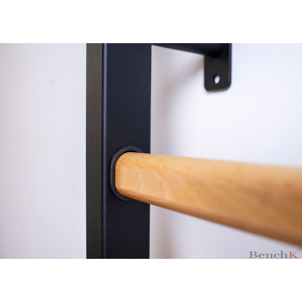 Nahaufnahme einer Sprosse der Sprossenwand. Holzsprosse in schwarzem Rahmen. BenchK-Logo unten rechts.