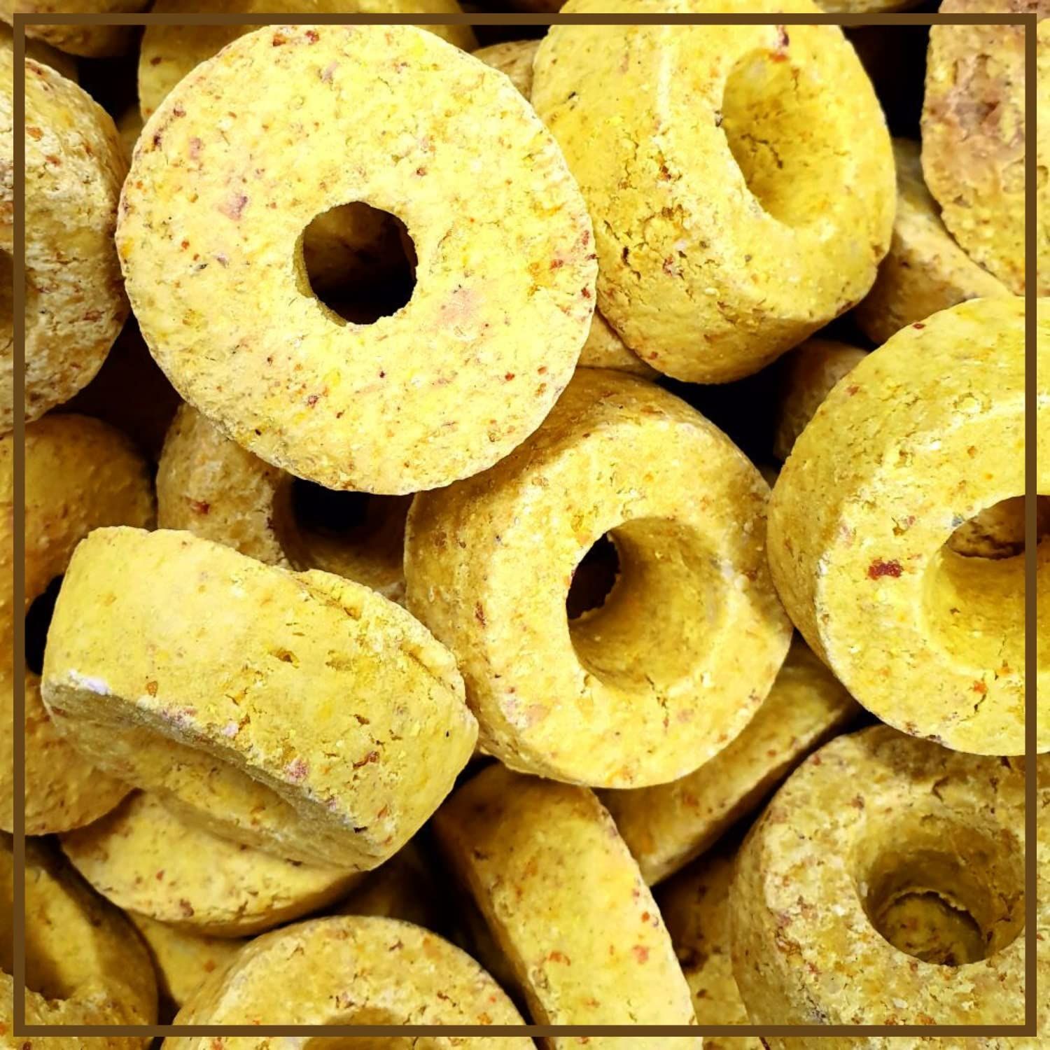 Gelbe, ringförmige Pferdeleckerlis mit Loch in der Mitte. Nahaufnahme, viele Leckerlis liegen zusammen.