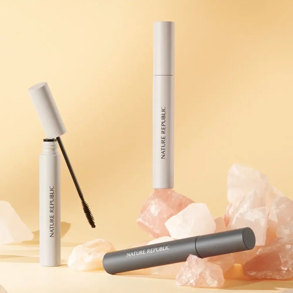 Drei Mascarahülsen auf Steinen. Zwei weiße und eine graue Hülse. Aufschrift NATURE REPUBLIC. Eine Hülse geöffnet.