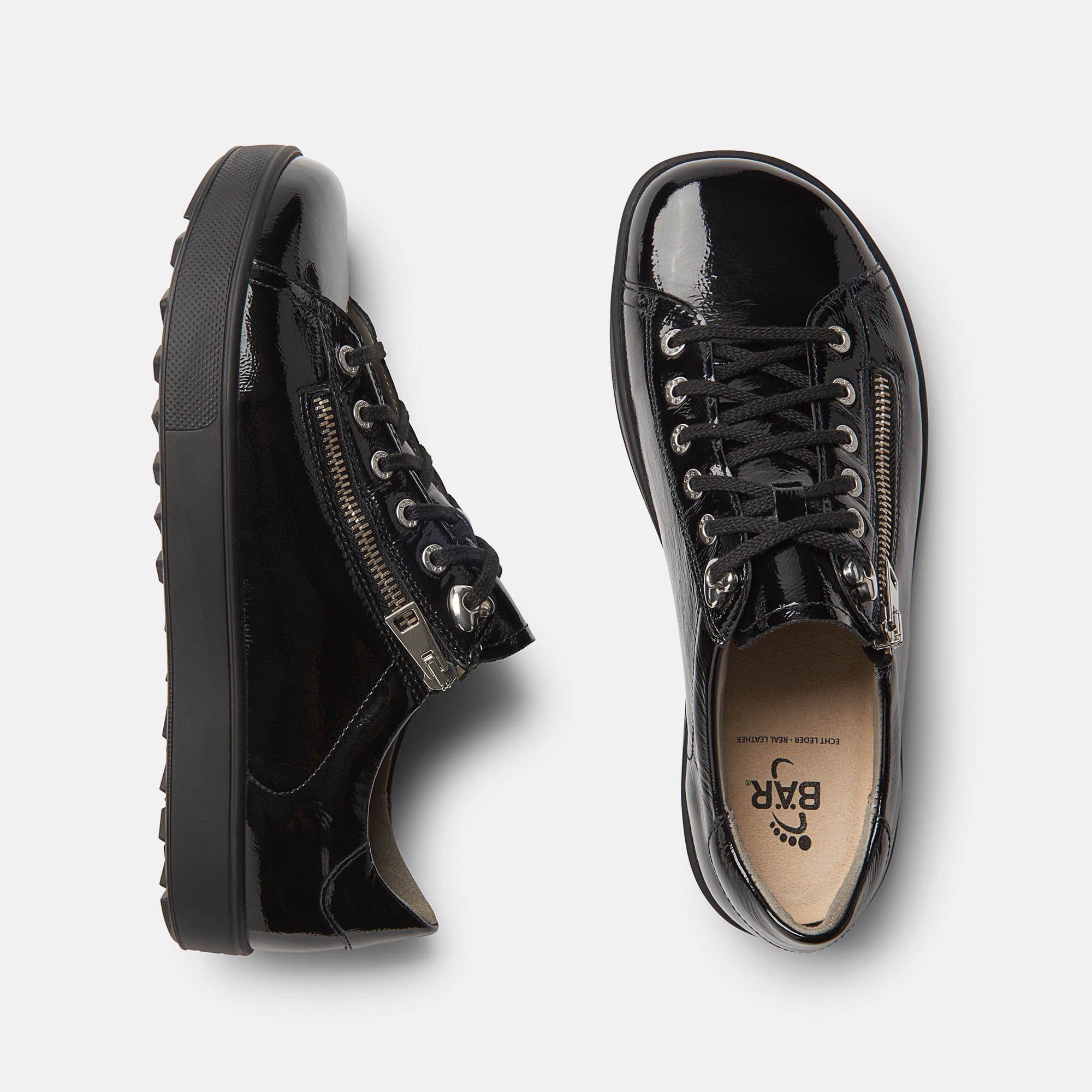 Draufsicht auf zwei schwarze Schuhe. Schnürsenkel, Reißverschluss und BÄR-Logo auf der Innensohle sichtbar.