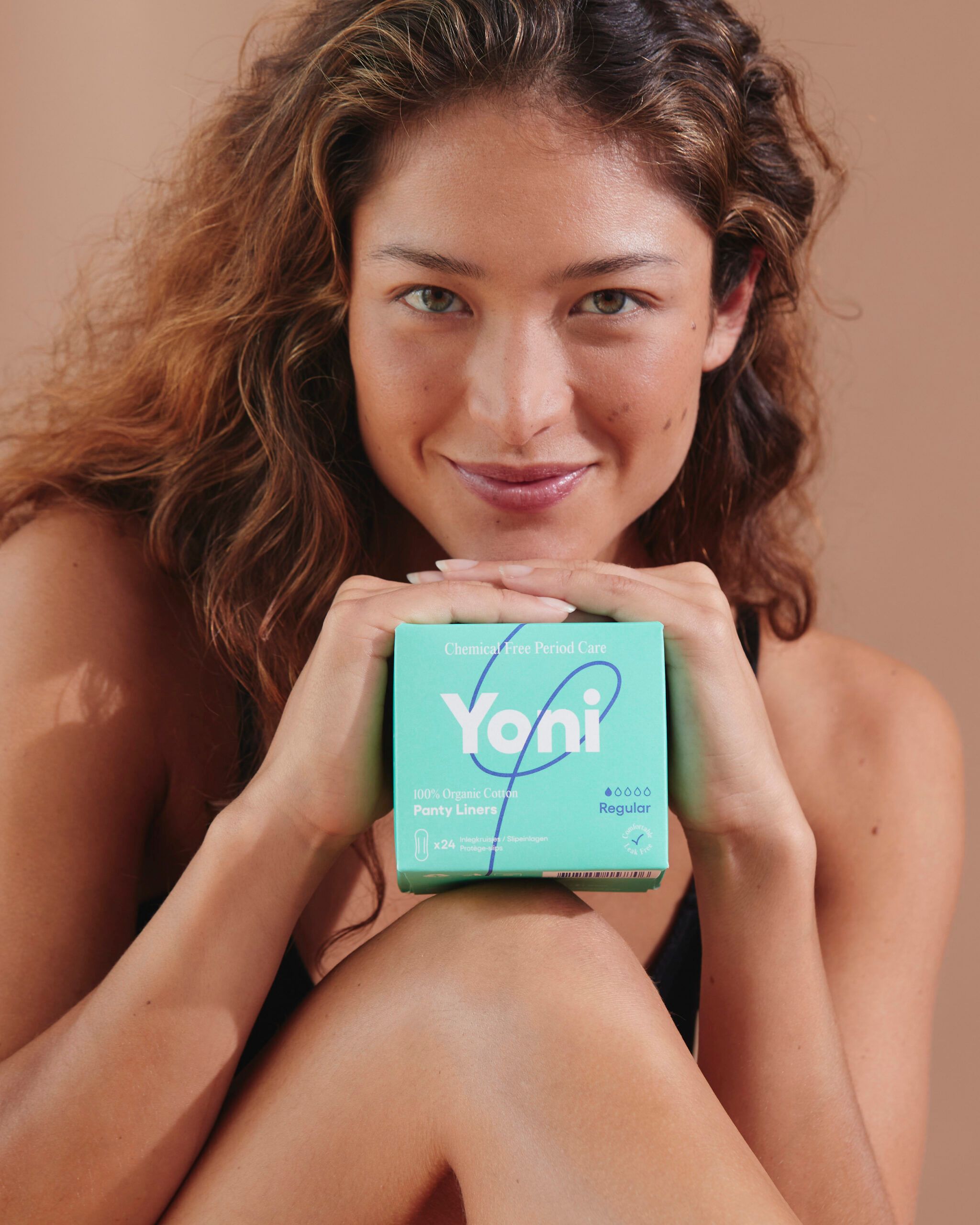 Frau hält eine grüne Schachtel mit Yoni Slipeinlagen. Aufschrift: 100% Bio-Baumwolle. Regular.