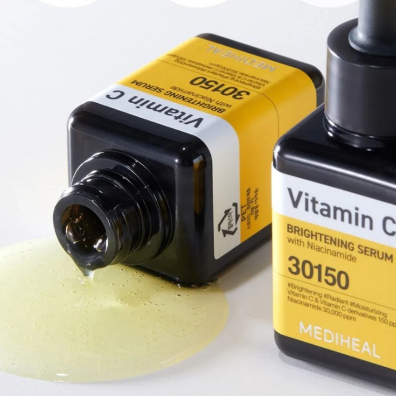 Zwei Flaschen Mediheal Vitamin C Serum, eine umgekippt mit austretendem Serum. Gelbe Etiketten mit schwarzer Schrift.