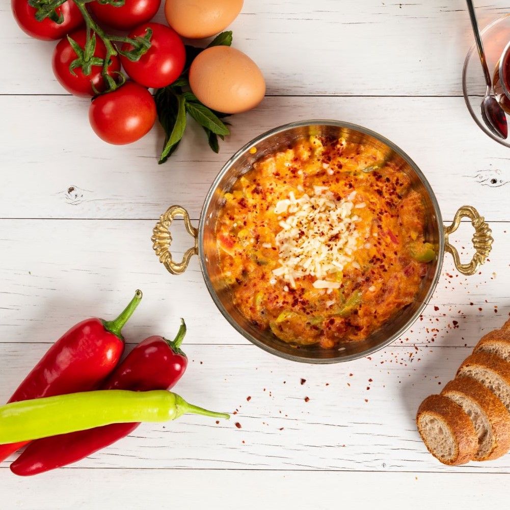 Pfanne mit Gericht, Tomaten, Eiern, Paprika, Brot. Goldene Griffe, rote und grüne Paprika, Eier, Brot.