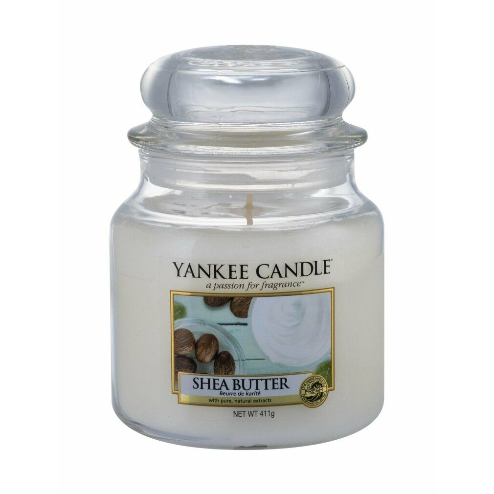 Yankee Candle Shea Butter Duftkerze. Glasbehälter mit Deckel. Etikett mit Produktname und Abbildung von Sheanüssen. Nettogewicht 411g.