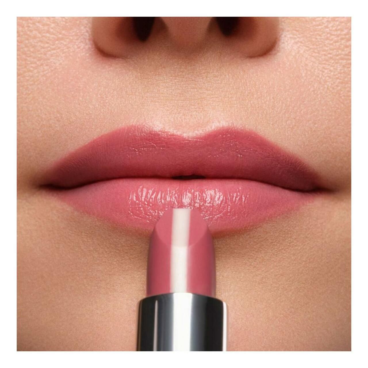 Lippenstift wird auf Lippen aufgetragen. Der Lippenstift hat eine rosa Farbe mit einem weißen Streifen in der Mitte. Der Lippenstift hat eine silberne Hülse.