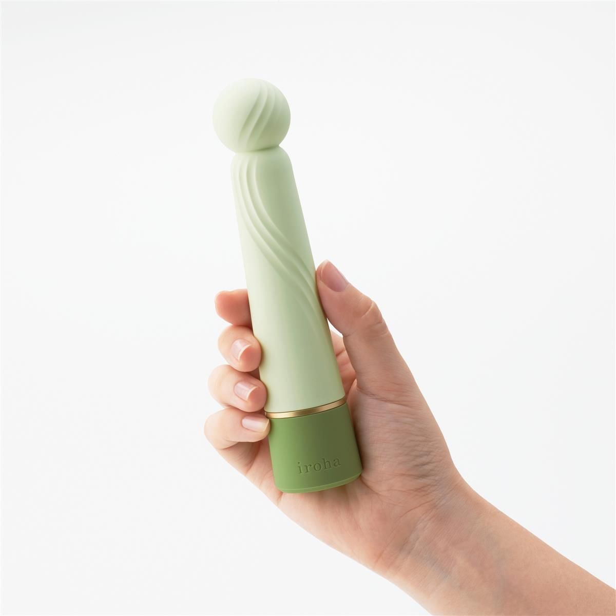 Hellgrüner Vibrator in Hand gehalten. Geriffelte Oberfläche, abgerundeter Kopf. Grünes Unterteil, goldener Ring. Aufschrift "iroha".