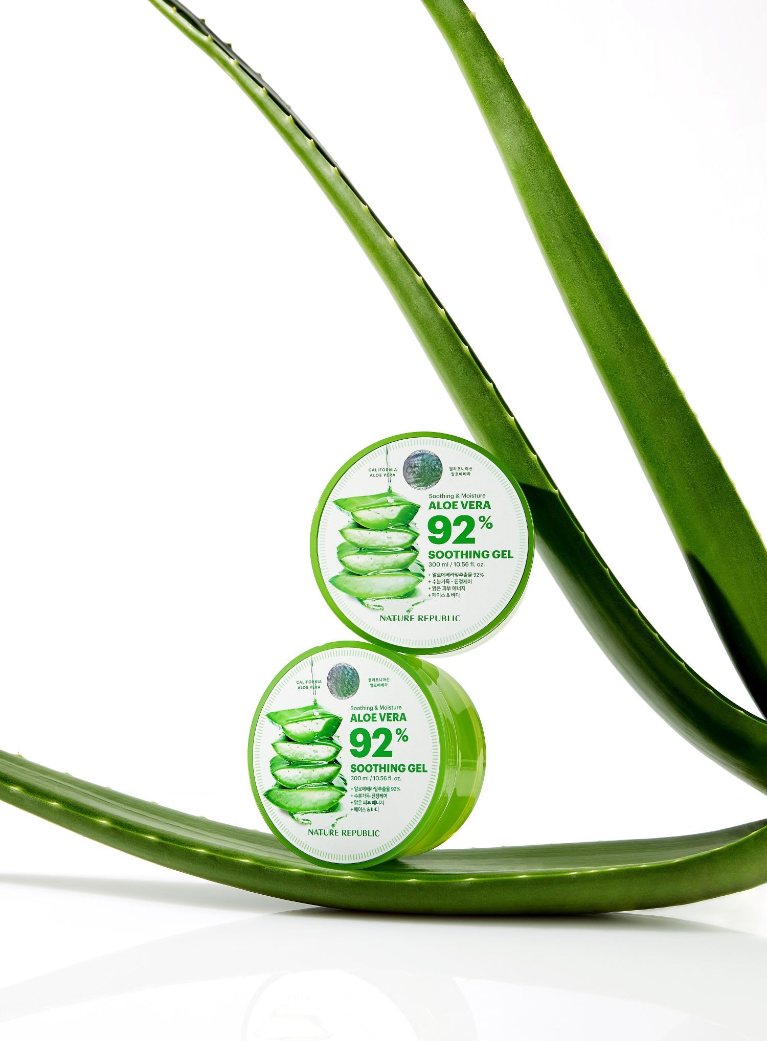 Zwei grüne Tiegel mit Deckel, auf einem Aloe Vera-Blatt. Aufkleber mit Text: "Soothing & Moisture Aloe Vera 92% Soothing Gel".
