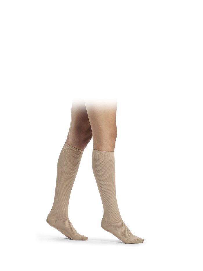 Beige Kniestrümpfe an Beinen. Die Strümpfe sind glatt und reichen bis unterhalb des Knies.