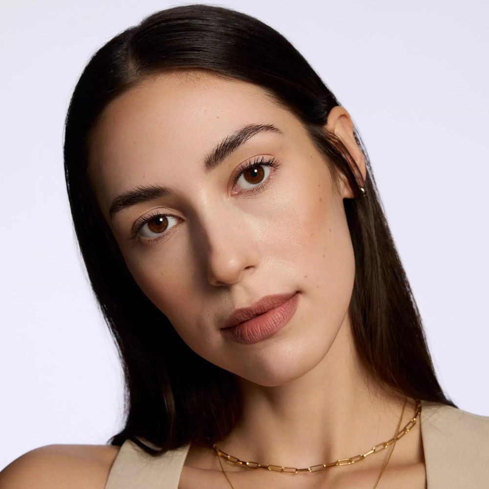 Porträt einer Frau mit Lippenstift. Sie trägt eine goldene Halskette. Natürliches Make-up.