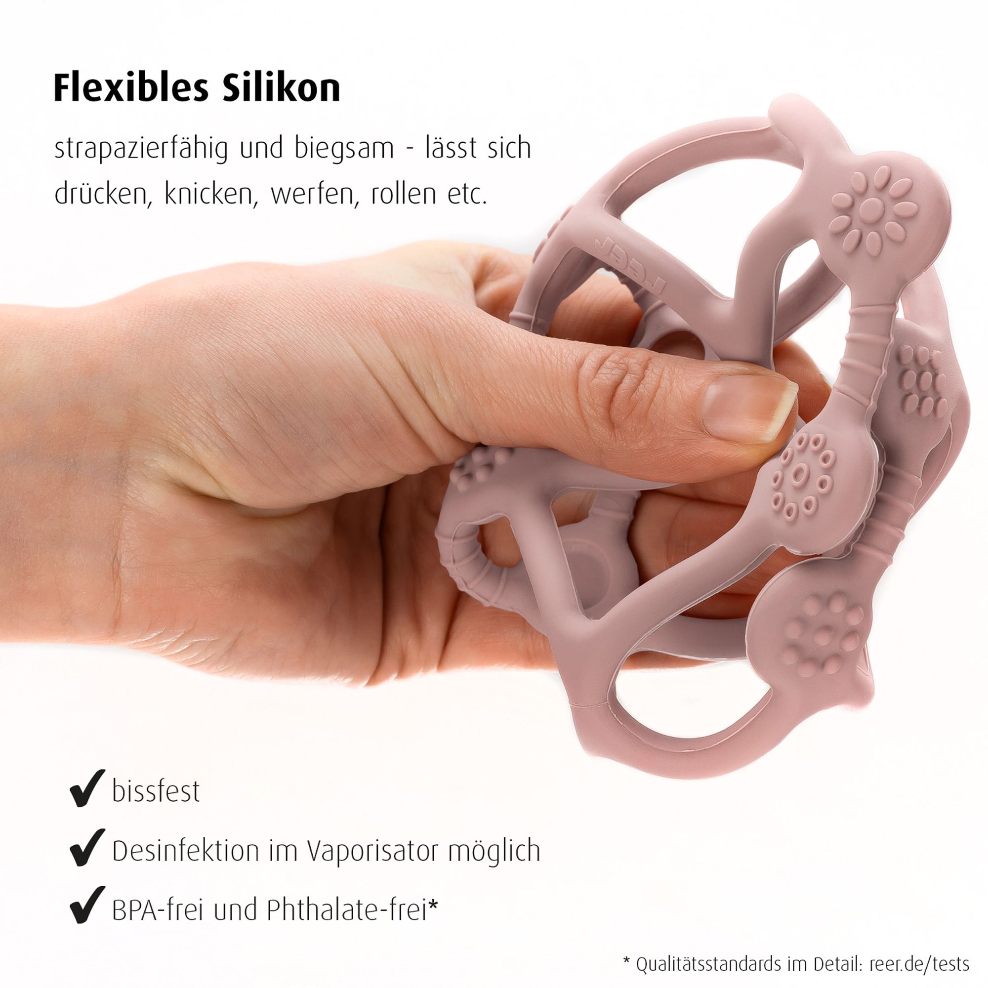 Eine Hand knetet einen flexiblen, rosafarbenen Beiß- und Greifball aus Silikon. Bissfest, desinfizierbar, BPA-frei.